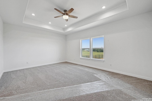 carpeted spare room featuring baseboards, a tray ceiling, recessed lighting, and ceiling fan