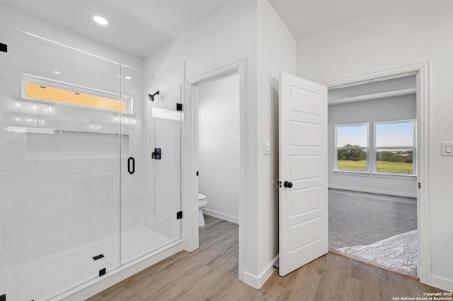 bathroom featuring a stall shower, toilet, baseboards, recessed lighting, and wood finished floors