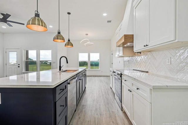 kitchen with light wood finished floors, a sink, decorative backsplash, appliances with stainless steel finishes, and white cabinetry