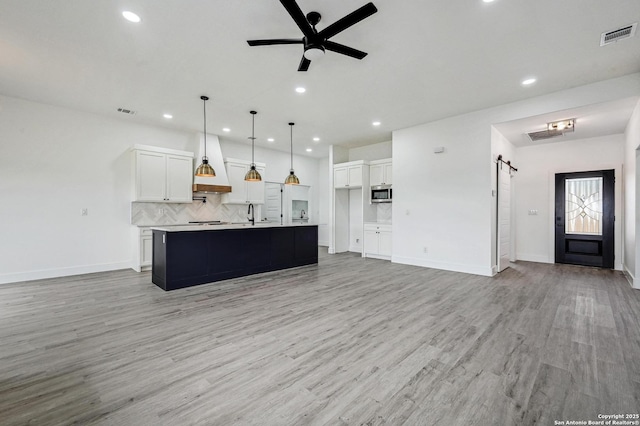 kitchen featuring white cabinets, backsplash, stainless steel microwave, and a barn door