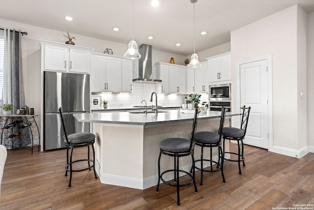 11206 Coppola, San Antonio, TX 78254 - kitchen featuring wall chimney range hood, decorative backsplash, a breakfast bar, appliances with stainless steel finishes, and dark wood-type flooring