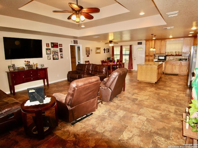 12365 Rudolph Rd, Atascosa, TX 78002 - living room with a tray ceiling, visible vents, a ceiling fan, stone finish flooring, and baseboards