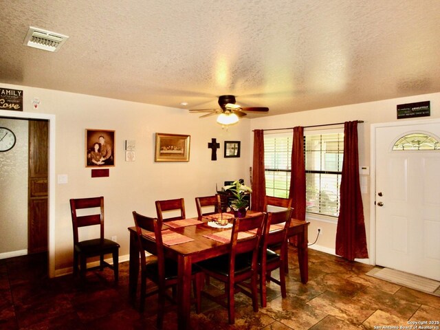 12365 Rudolph Rd, Atascosa, TX 78002 - dining room featuring a textured ceiling, a ceiling fan, baseboards, and visible vents