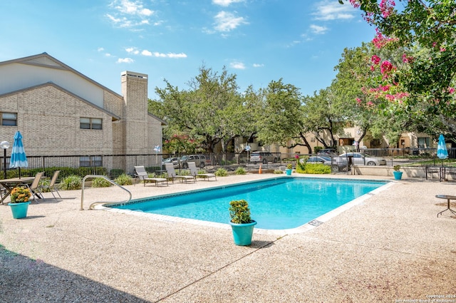 pool with a patio area and fence