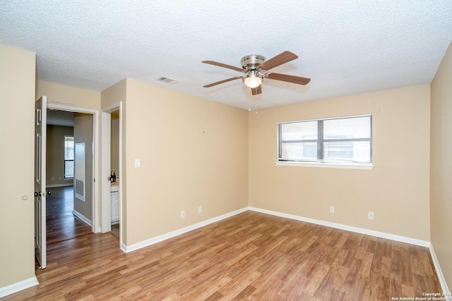 unfurnished room featuring plenty of natural light, ceiling fan, visible vents, and light wood-style flooring