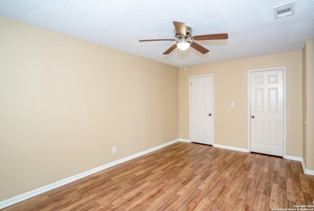 unfurnished bedroom featuring light wood finished floors, a textured ceiling, baseboards, visible vents, and ceiling fan