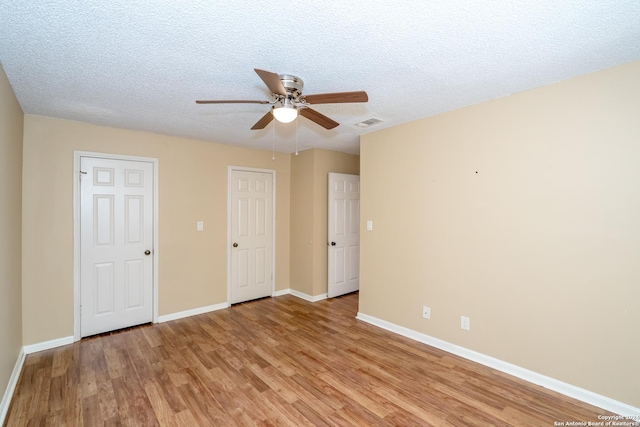 spare room with baseboards, a ceiling fan, a textured ceiling, and light wood-type flooring