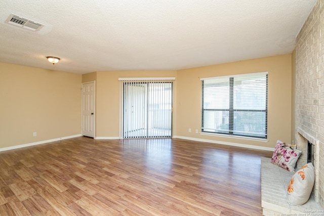 unfurnished living room with a fireplace, baseboards, visible vents, and light wood-type flooring