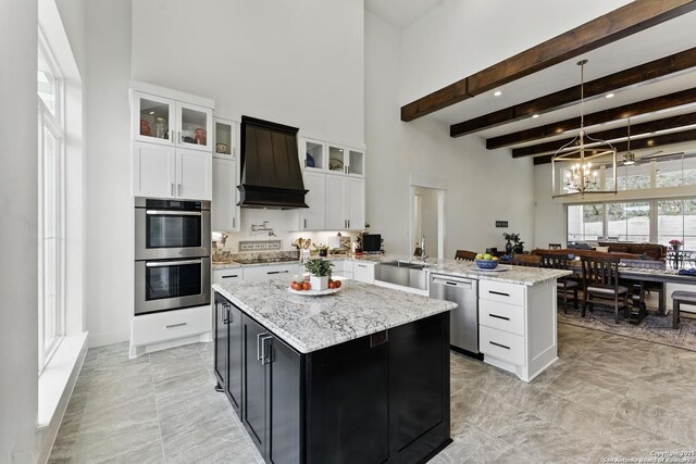 kitchen featuring stainless steel appliances, a sink, a towering ceiling, custom exhaust hood, and an inviting chandelier