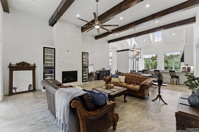 living area featuring ceiling fan with notable chandelier, a towering ceiling, beam ceiling, and recessed lighting