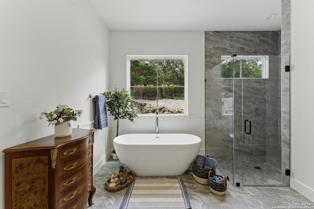 bathroom featuring a freestanding bath, baseboards, a healthy amount of sunlight, and a stall shower