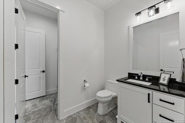 half bath with toilet, vanity, and baseboards