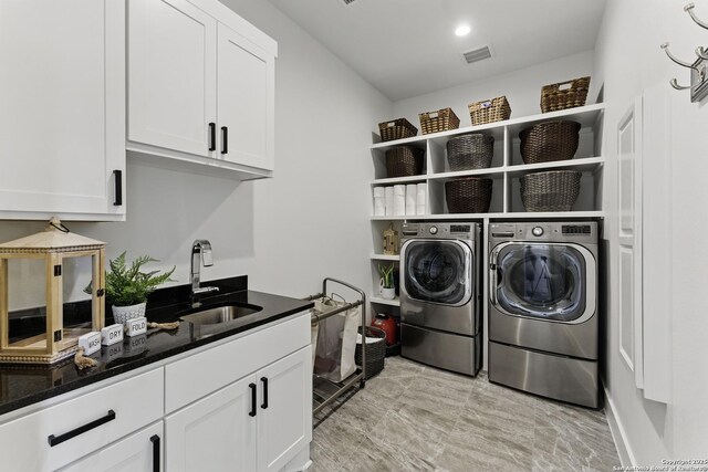 clothes washing area featuring washer and dryer, cabinet space, a sink, and visible vents