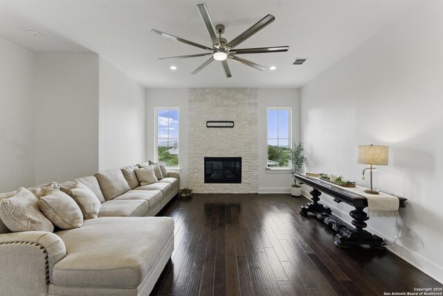 living room featuring ceiling fan, a wealth of natural light, a stone fireplace, and visible vents