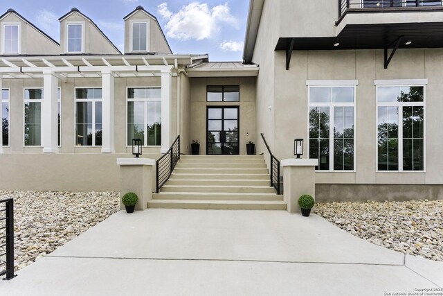 entrance to property with metal roof, a standing seam roof, and stucco siding