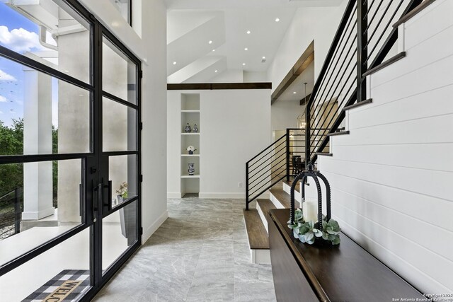 corridor featuring recessed lighting, a towering ceiling, french doors, baseboards, and stairs