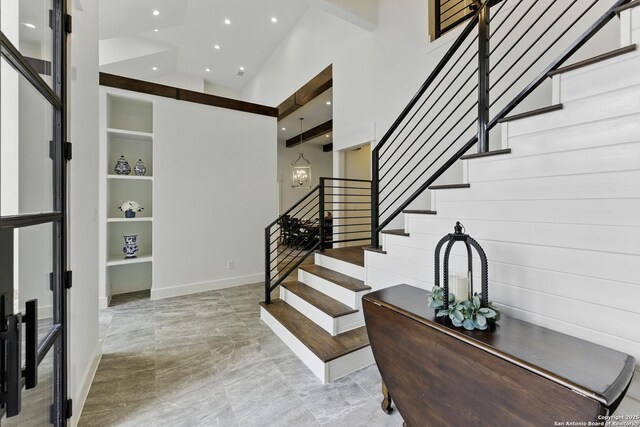 entryway featuring baseboards, a high ceiling, stairs, and recessed lighting