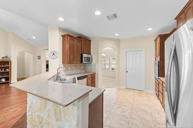 108 County Road 4325, Hondo, TX 78861 - kitchen featuring backsplash, a sink, arched walkways, a peninsula, and appliances with stainless steel finishes