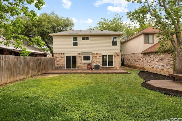 back of house with central AC, fence, a wooden deck, brick siding, and a lawn