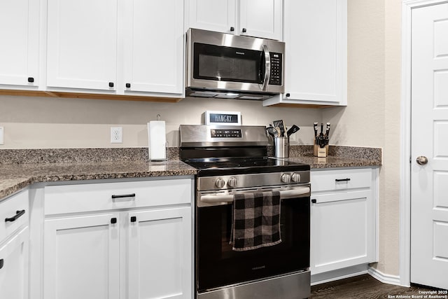 kitchen featuring dark stone countertops, dark wood-style floors, white cabinetry, and appliances with stainless steel finishes