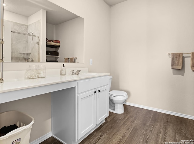 bathroom featuring baseboards, vanity, wood finished floors, and a stall shower