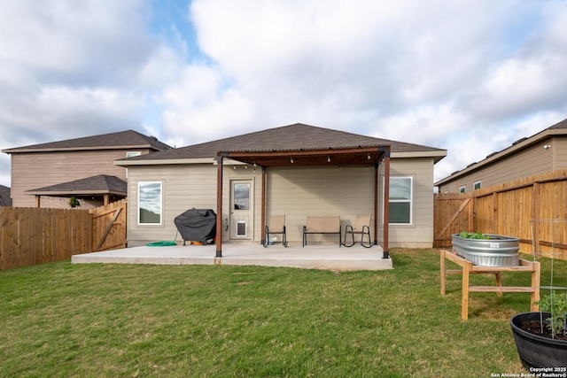 back of property with a yard, a patio area, and a fenced backyard