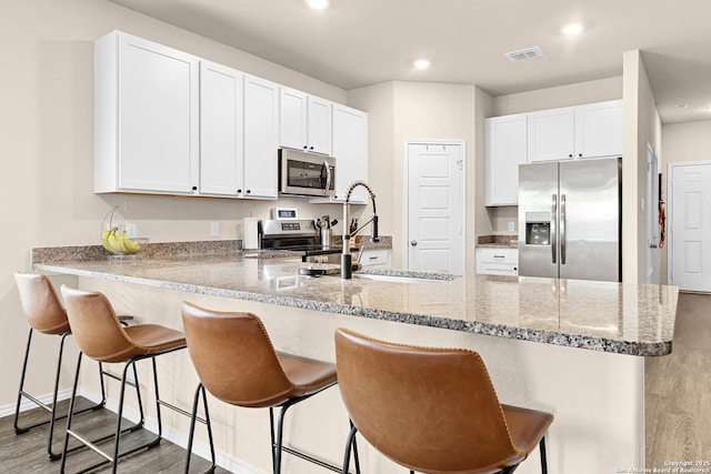 kitchen with white cabinets, recessed lighting, stainless steel appliances, visible vents, and a peninsula