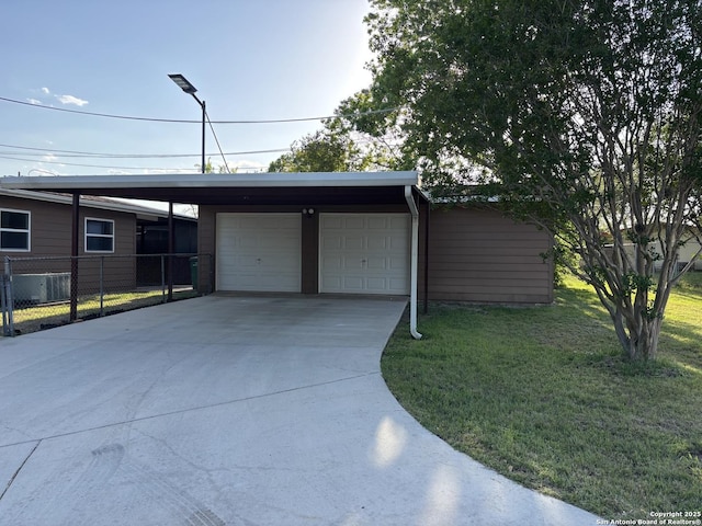 garage featuring concrete driveway and fence