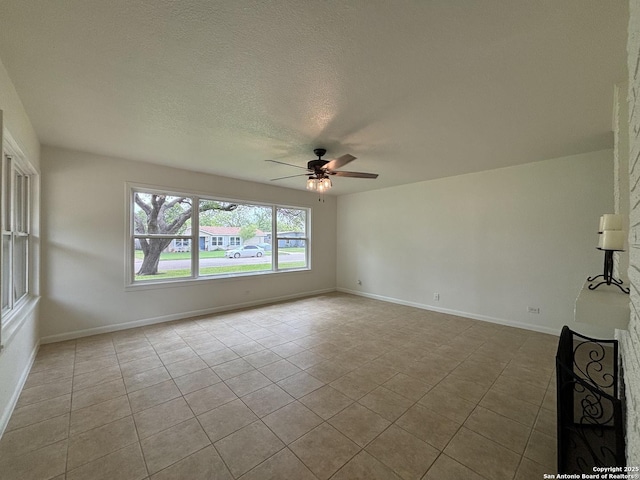 tiled empty room with a textured ceiling, baseboards, and ceiling fan