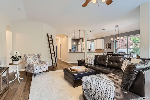 living area featuring baseboards, arched walkways, wood finished floors, and ceiling fan with notable chandelier
