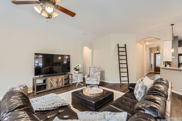 living area featuring ceiling fan, arched walkways, wood finished floors, and baseboards