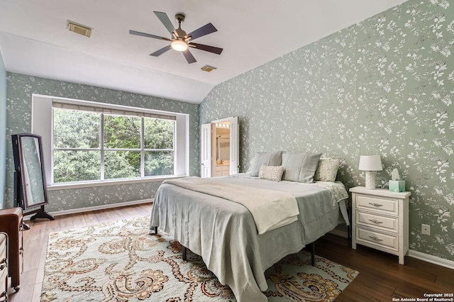 bedroom with vaulted ceiling, visible vents, wood finished floors, and wallpapered walls