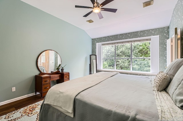 bedroom featuring baseboards, lofted ceiling, wood finished floors, and visible vents