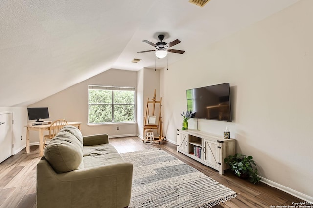 living room featuring vaulted ceiling, visible vents, baseboards, a ceiling fan, and wood finished floors