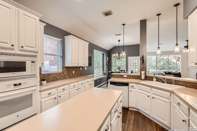 kitchen with vaulted ceiling, a sink, white appliances, dark wood-style flooring, and visible vents