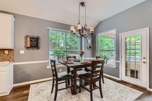dining area featuring lofted ceiling, baseboards, wood finished floors, and a notable chandelier