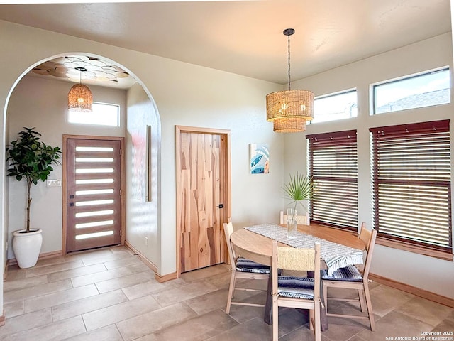 dining area with baseboards, arched walkways, and a notable chandelier