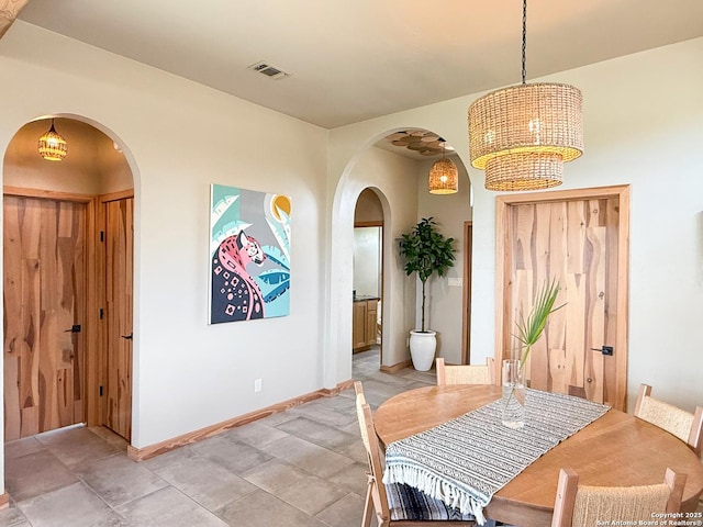 dining area with arched walkways, visible vents, baseboards, and an inviting chandelier