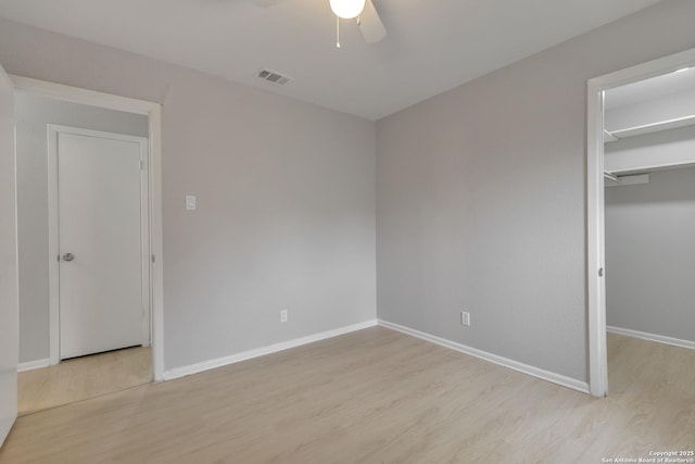 1051 Country Clb Unit 20, Seguin, TX 78155 - unfurnished bedroom with visible vents, a ceiling fan, a walk in closet, baseboards, and light wood-style flooring