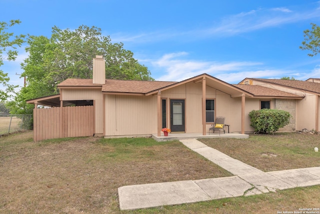 1051 Country Clb Unit 20, Seguin, TX 78155 - view of front of home with a front yard, a shingled roof, a chimney, and fence