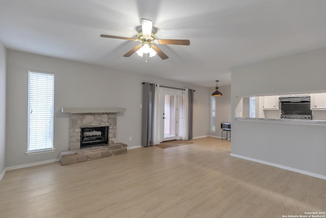1051 Country Clb Unit 20, Seguin, TX 78155 - unfurnished living room with baseboards, a ceiling fan, light wood-type flooring, and a fireplace