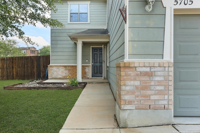 entrance to property with a yard, a shingled roof, and fence