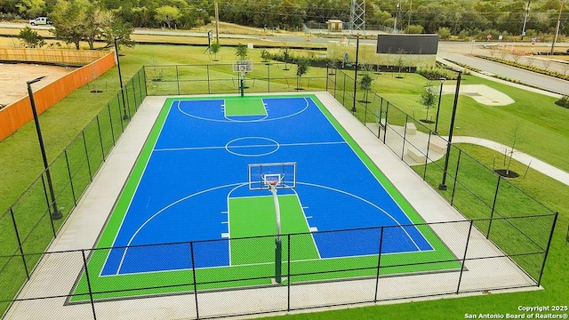 view of basketball court featuring a yard, community basketball court, and fence