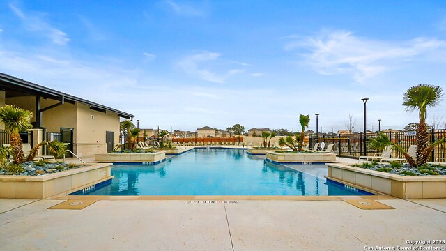 community pool with fence and a patio