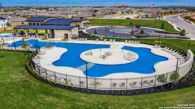 pool with a residential view, a lawn, and fence