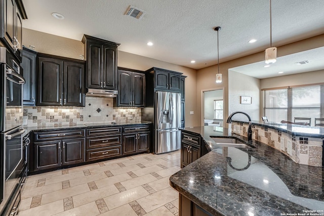 kitchen featuring dark stone countertops, a sink, decorative backsplash, appliances with stainless steel finishes, and visible vents