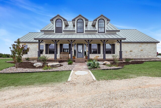 view of front facade with stone siding, a standing seam roof, covered porch, and metal roof