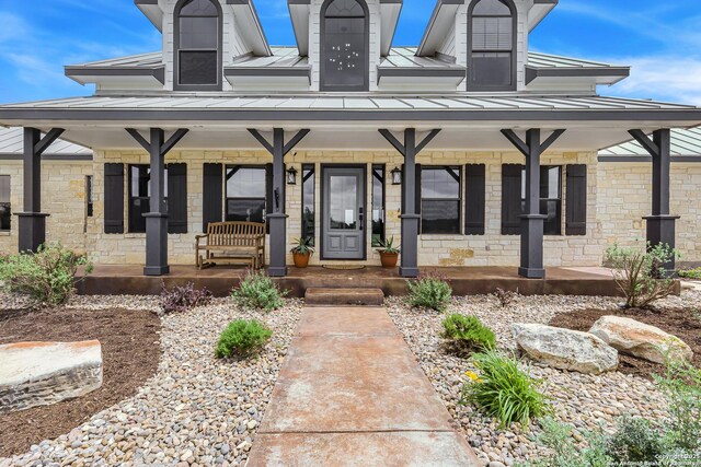exterior space with metal roof, stone siding, a standing seam roof, and covered porch