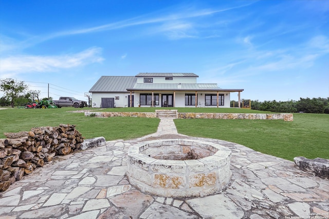 exterior space with a standing seam roof, a porch, a lawn, a fire pit, and metal roof