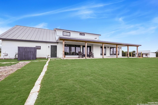 rear view of house featuring a yard, a standing seam roof, a patio area, and metal roof